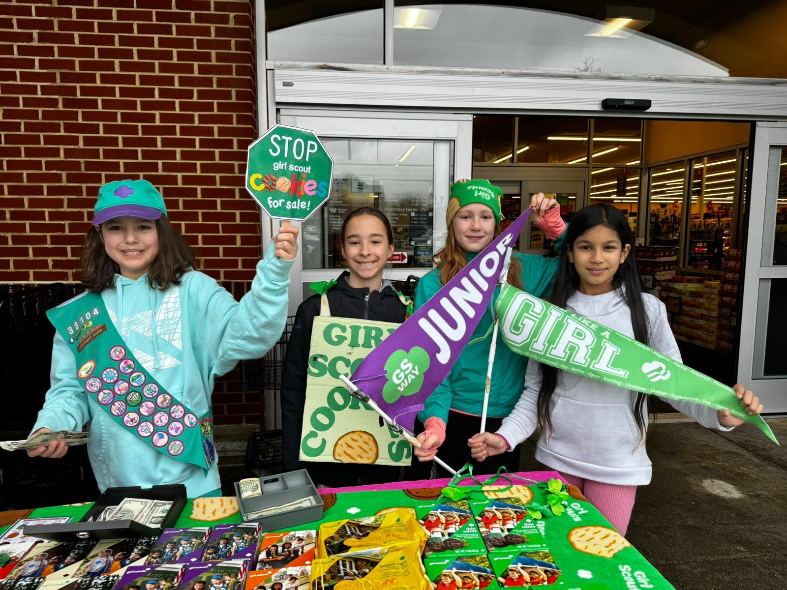 Junior Girl Scouts holding pennants at their cookie booth