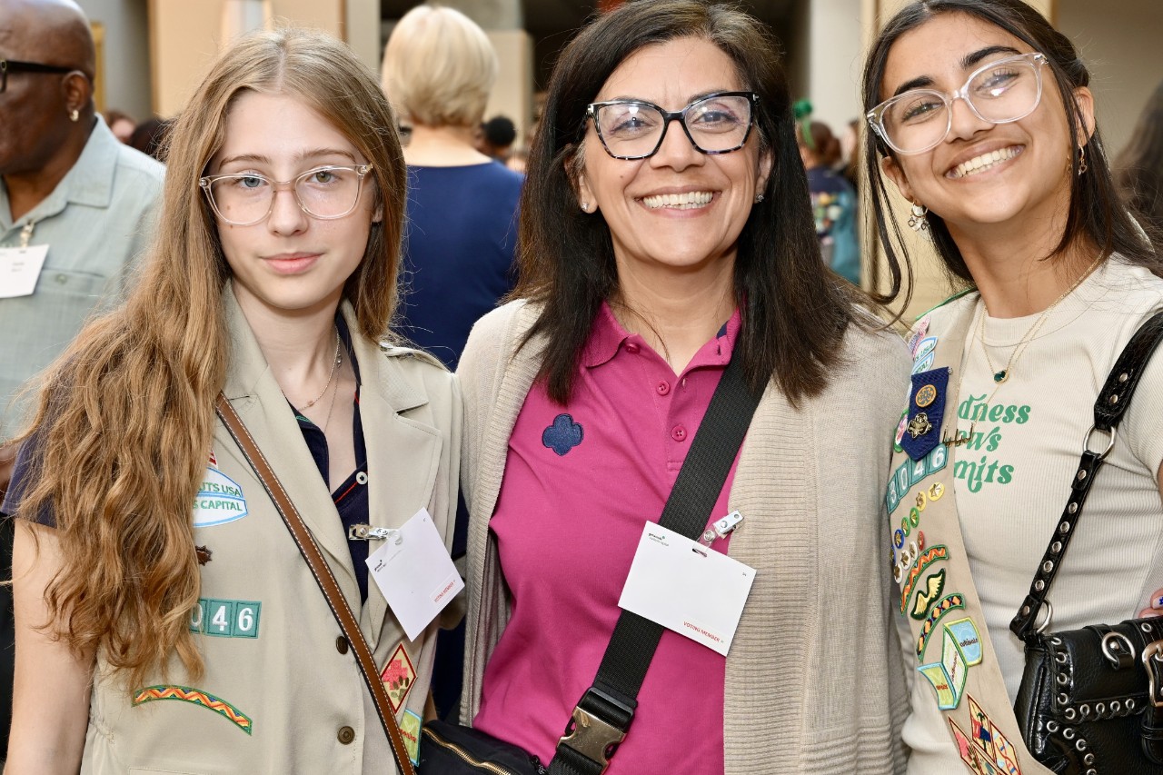 One woman and two younger Girl Scouts stand together at an event
